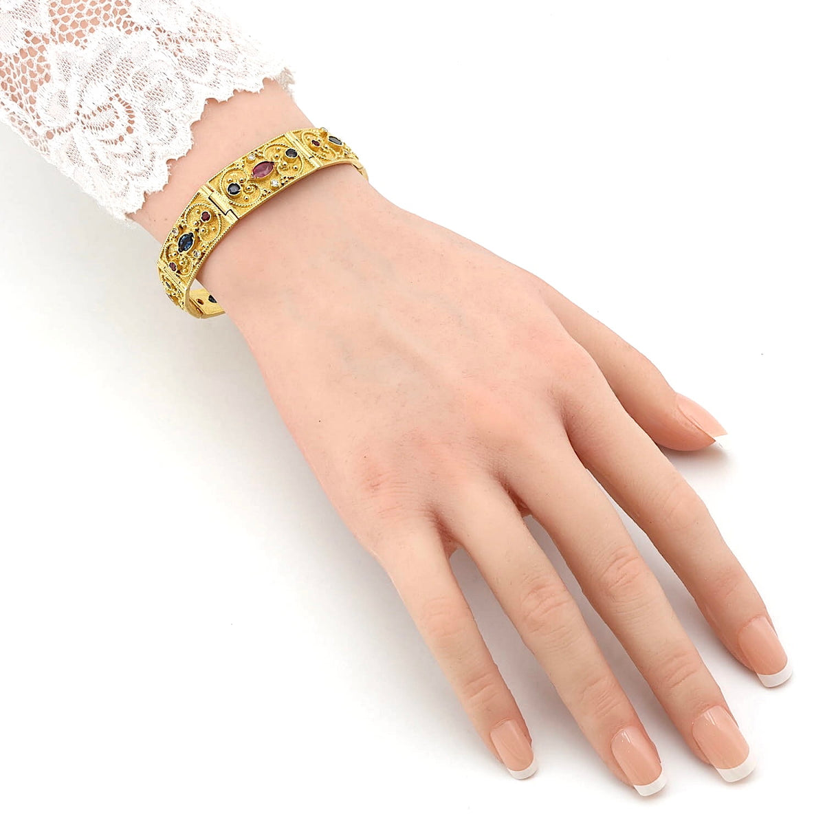 Armband in 750er Gelbgold mit Brillanten, Rubinen und blauen Saphiren, an einem künstlichen Arm