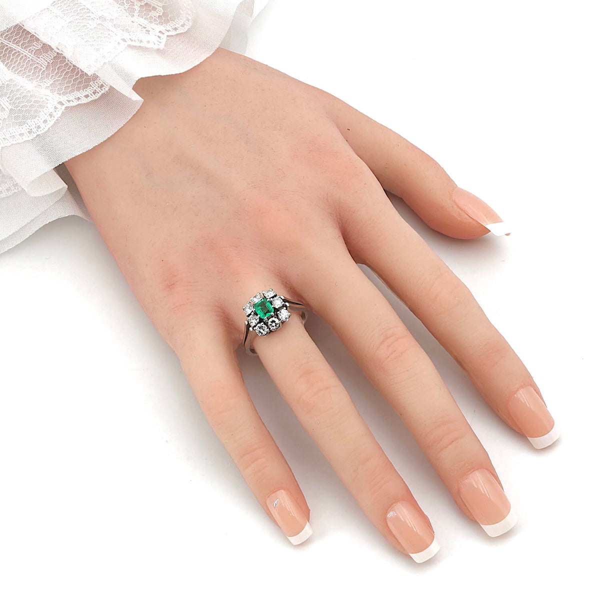 RIng in 750er Weißgold mit einem Smaragd und Brillanten gesamt ca. 0,90 ct, an einer künstlichen Hand