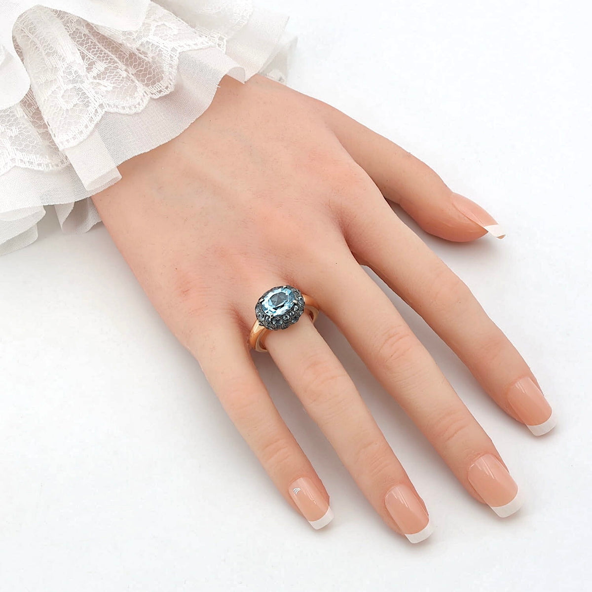 Pomellato Ring „Tabou“ in 750er Gold und 925er Silber mit blauen Topasen, an einer künstlichen Hand