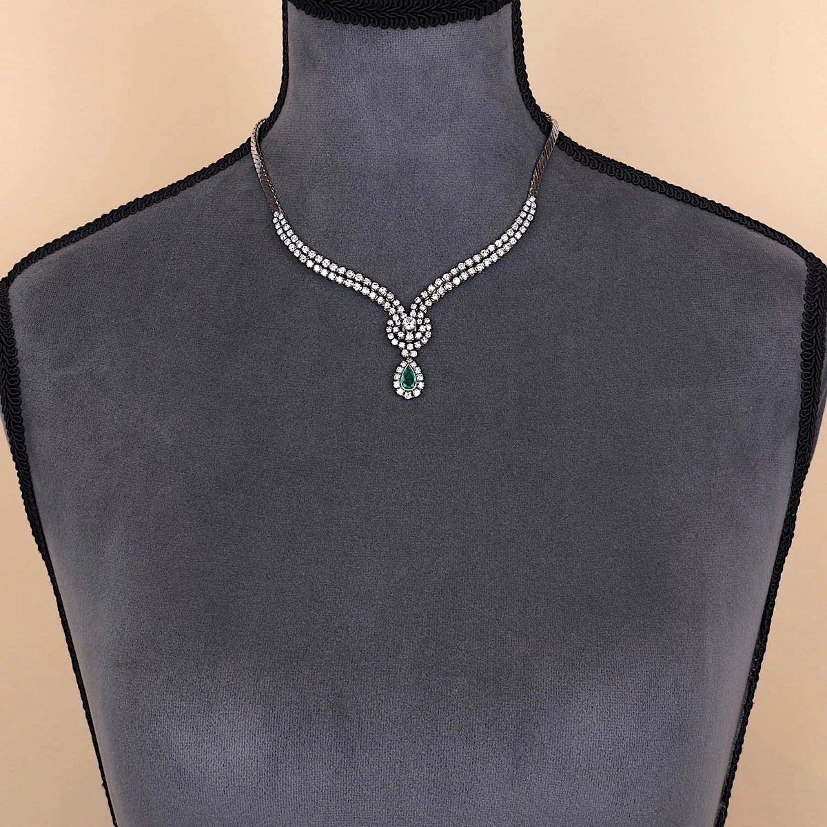 Juwelen-Collier in 750er Weißgold mit ca. 7,0 ct Brillanten und einem Smaragd, an einer dunklen Büste